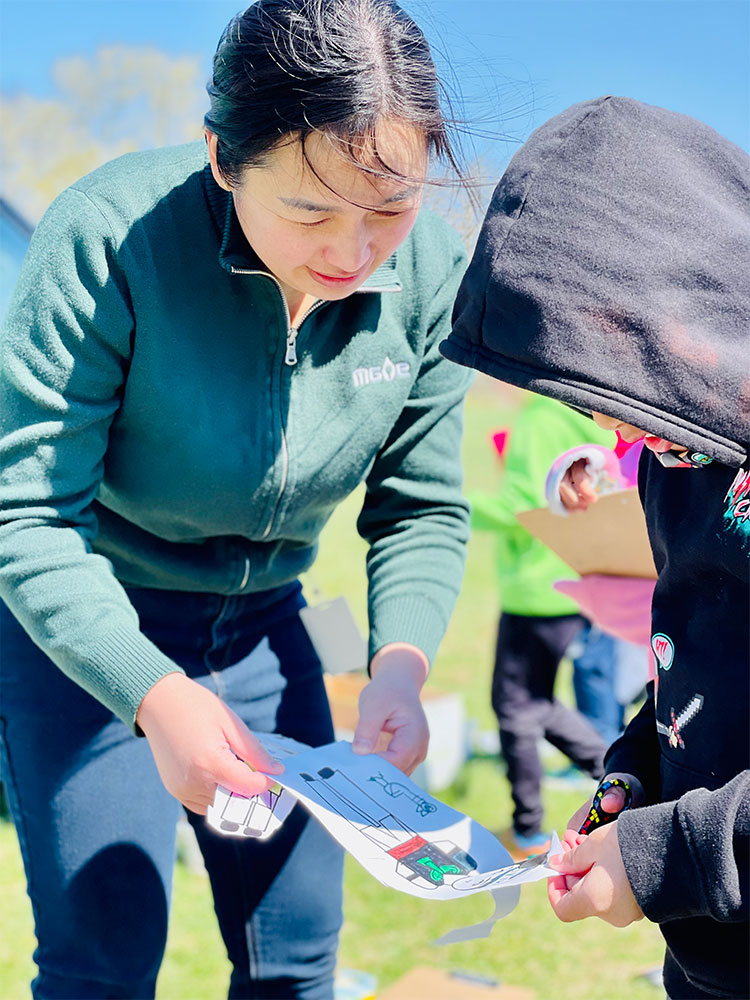 Mai Thao helps a student cut out a character from the Hmong coloring book.