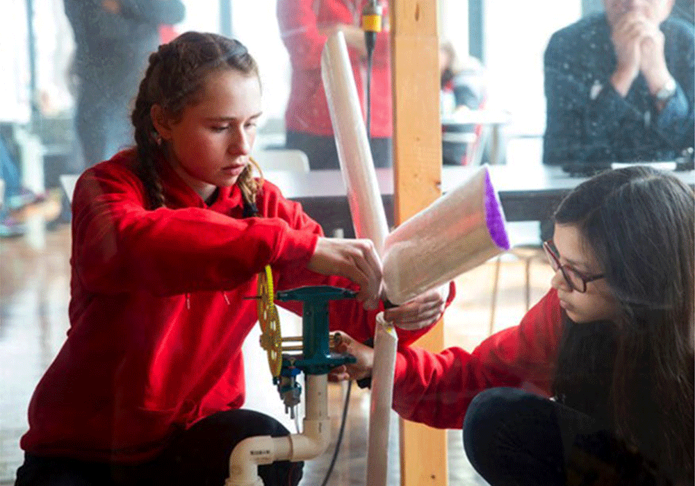 two young teenage girls engineering a windmill device