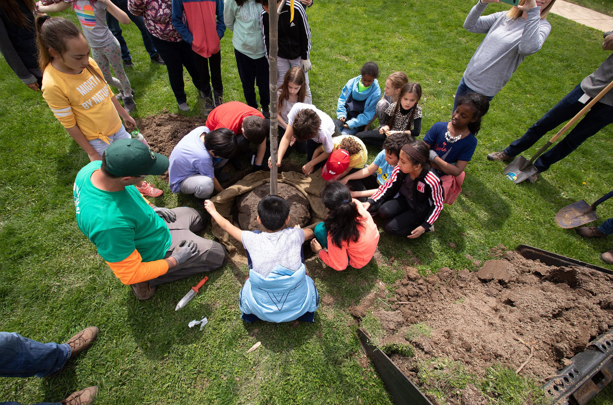 Students plant a tree with MGE.