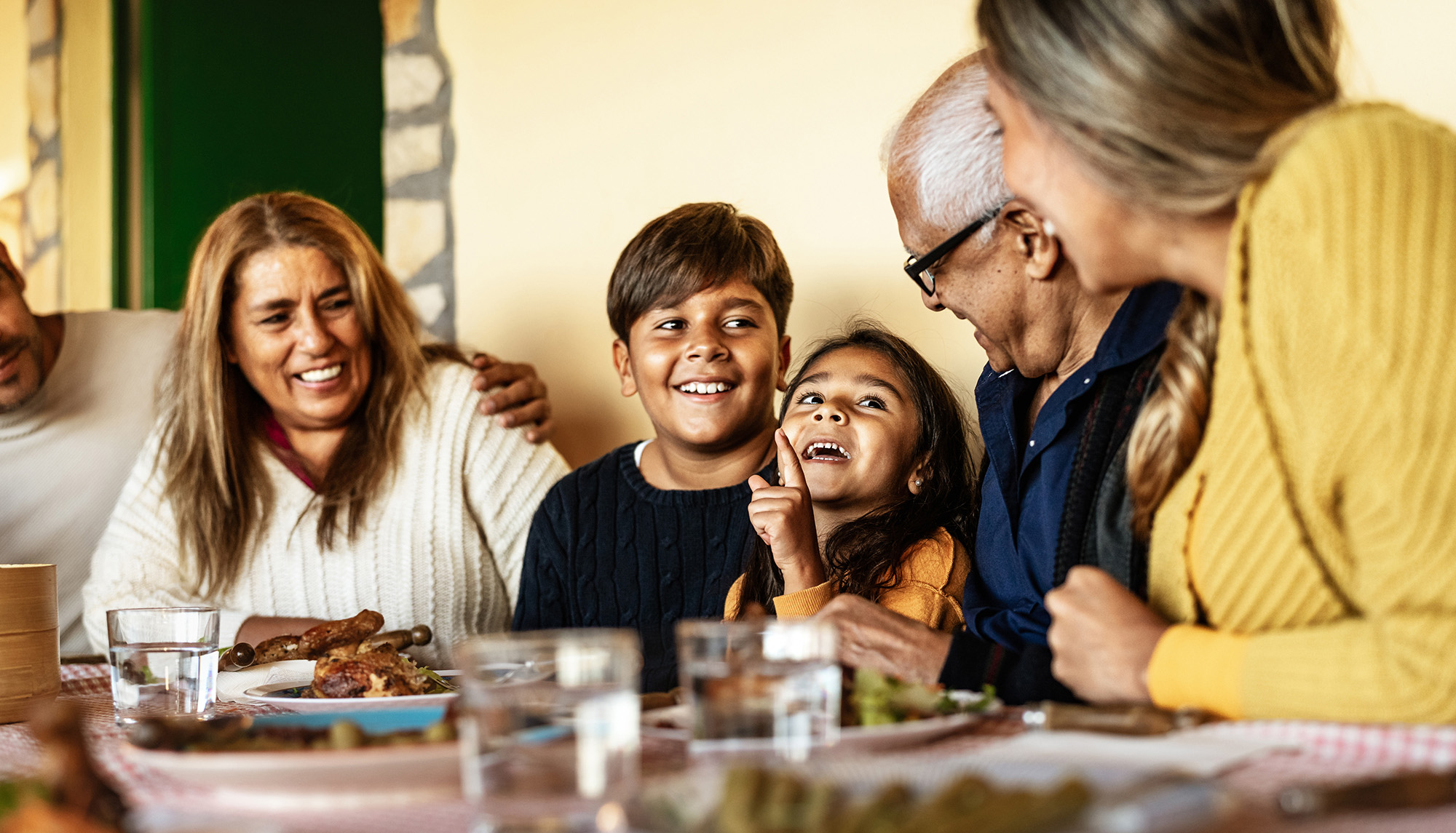 Family laughing at dinner table.