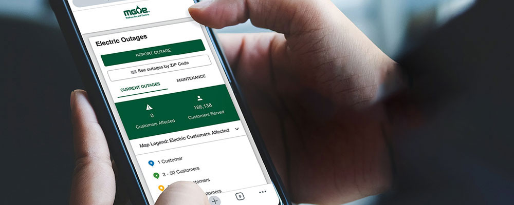 Close-up of someone looking at MGE's outage map page on their smartphone in the dark.