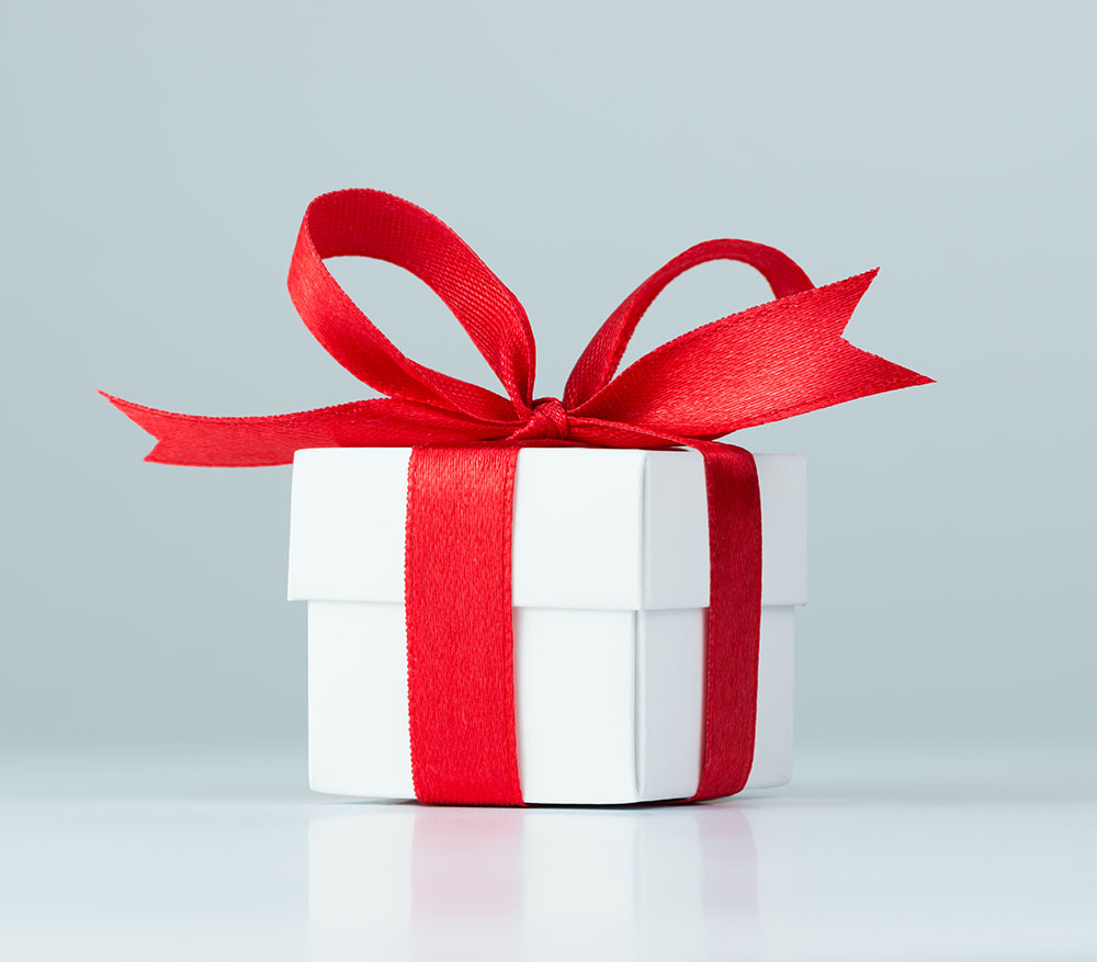 White gift box wrapped with red ribbon bow.