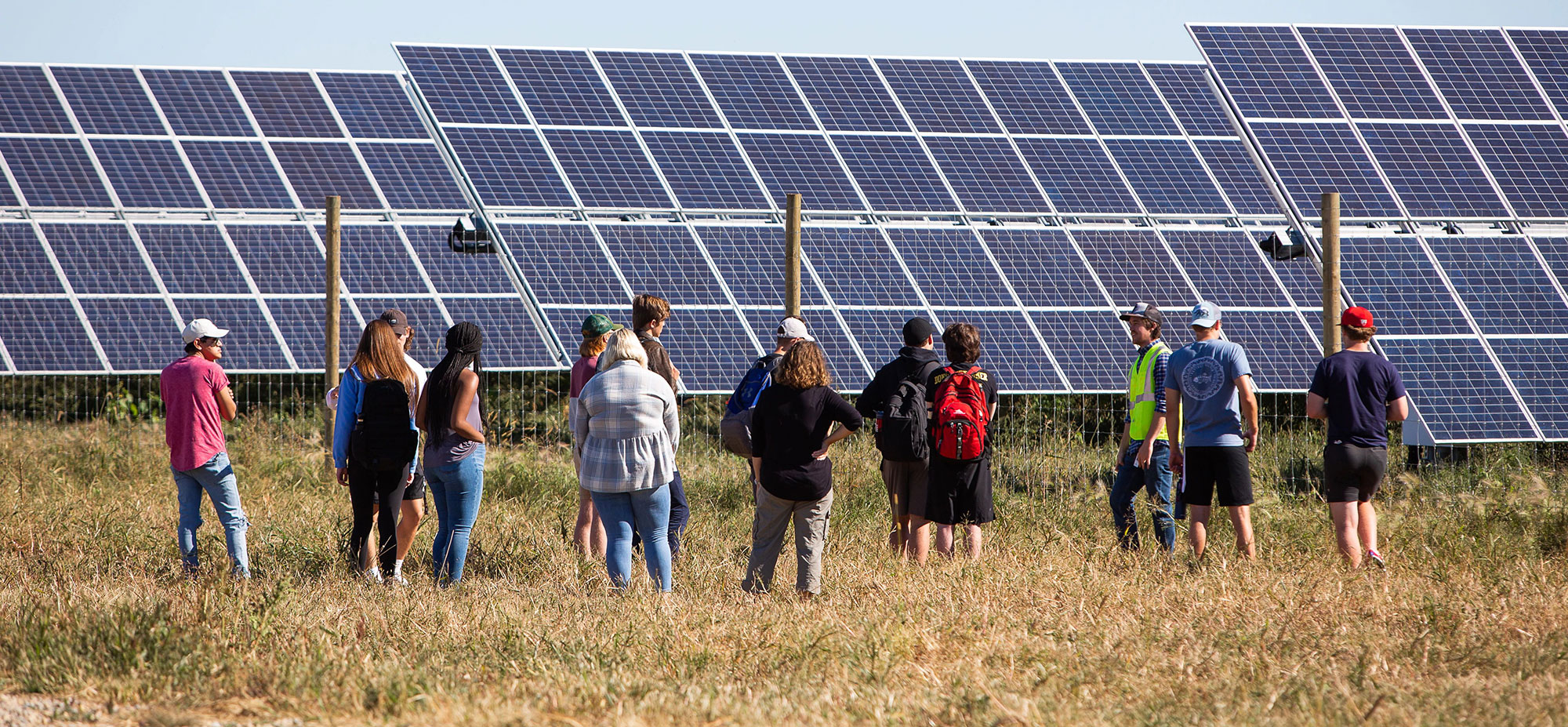 Group of people in front of large solar array.