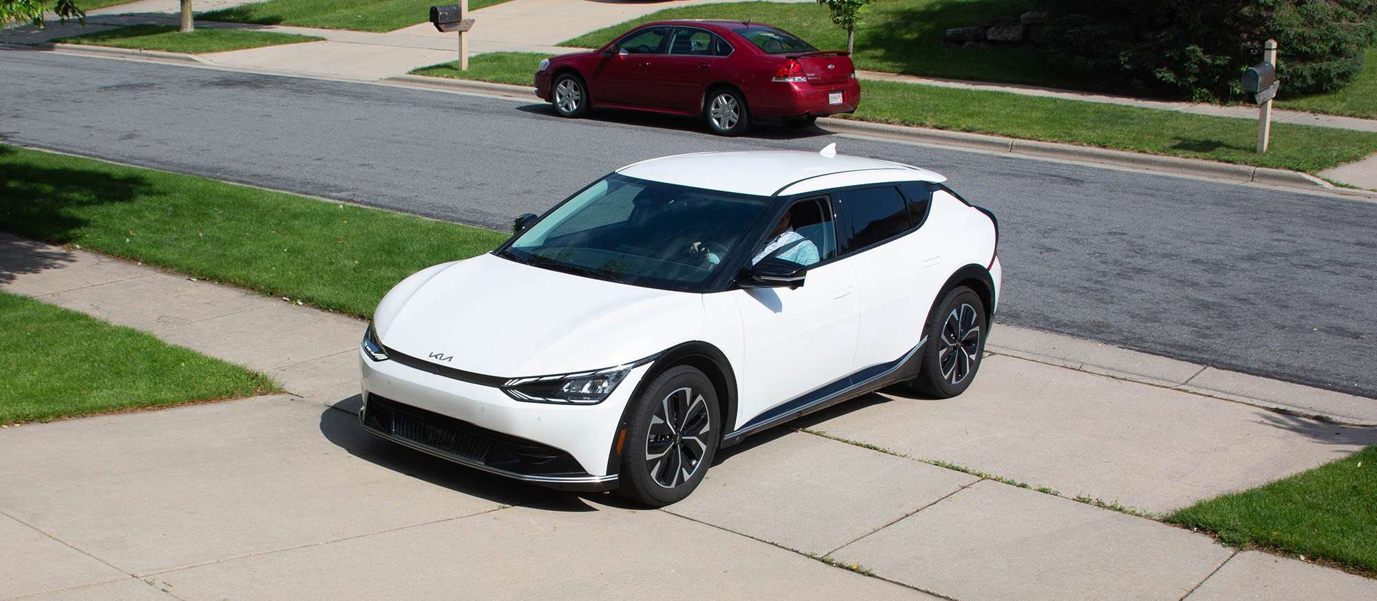 Person pulling into driveway in an electric vehicle.