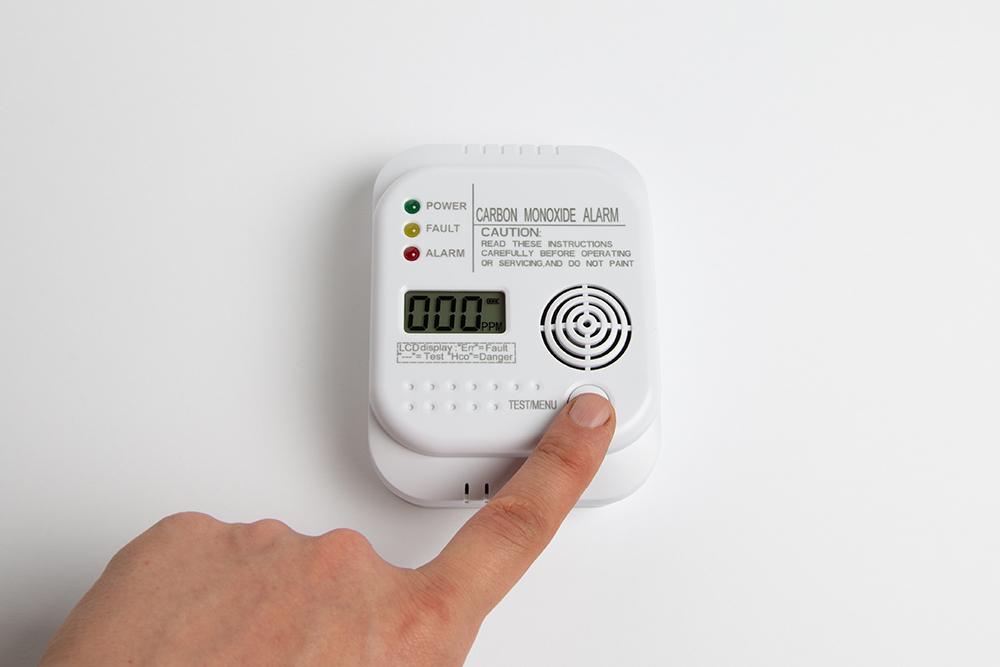 Testing a carbon monoxide detector mounted to a wall.