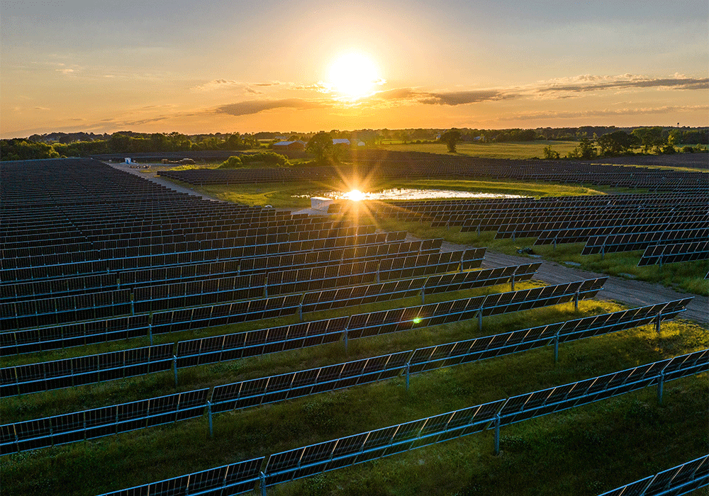 An aerial view of solar panels at the Paris Solar-Battery Park with the sun shining on the horizon.