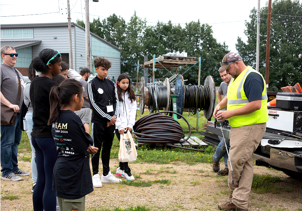 MGE lineman demonstrating his job to teenagers.