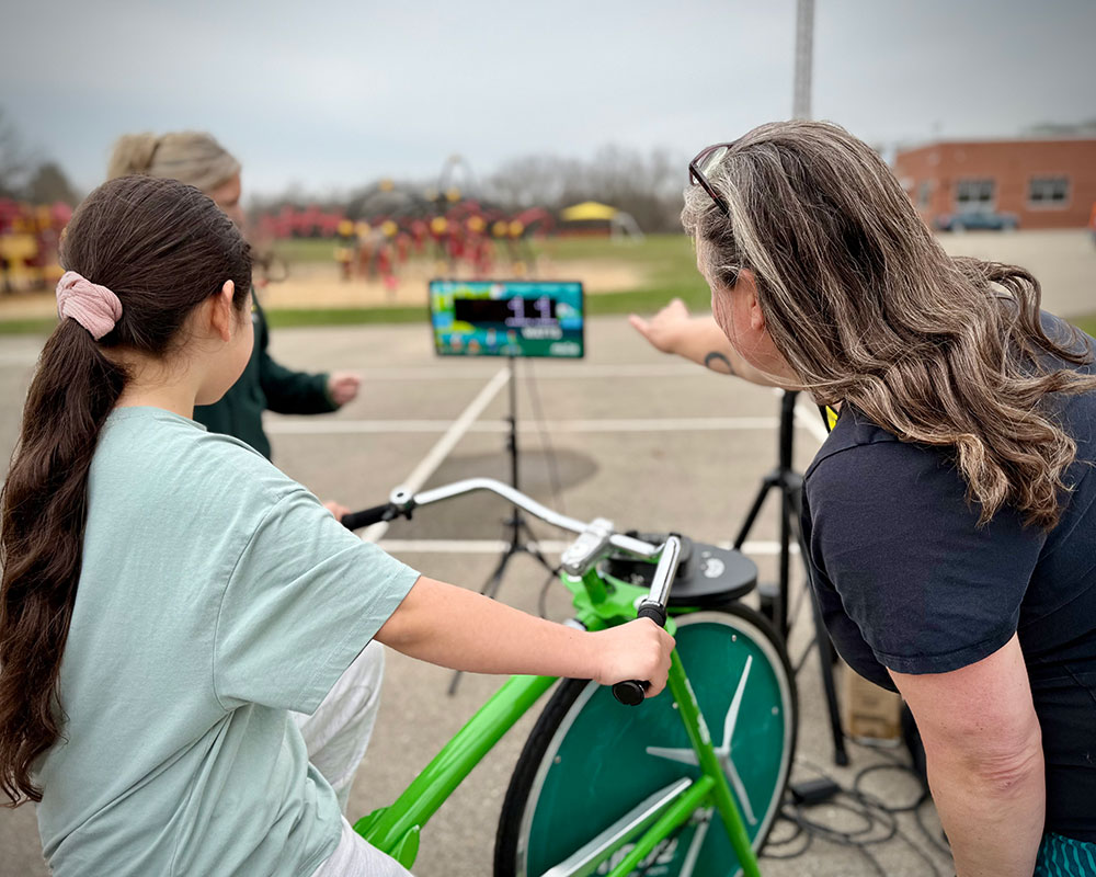 MGE Energy Experts help a student with the Power Pedal Bicycle